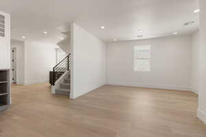 Unfurnished room featuring stairs, light wood-type flooring, and recessed lighting