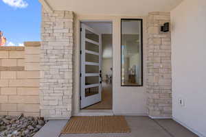 Entrance to property with stucco siding and stone siding