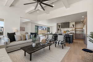 Living room featuring beamed ceiling, light wood-style floors, a ceiling fan, and recessed lighting