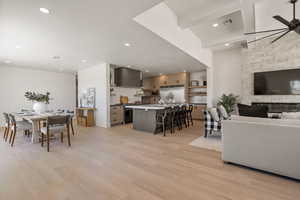 Dining space featuring light wood finished floors, a ceiling fan, recessed lighting, and a fireplace