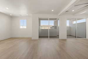 Unfurnished bedroom featuring multiple windows, light wood-style flooring, recessed lighting, beam ceiling, and access to exterior