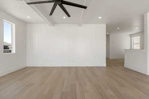 Spare room with beamed ceiling, light wood-type flooring, wood walls, ceiling fan, and recessed lighting