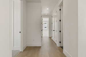 Corridor featuring light wood finished floors and recessed lighting