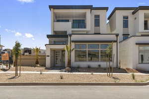 Contemporary home with stucco siding, stone siding, and a balcony