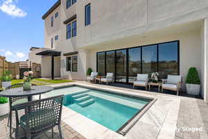 Rear view of property featuring a patio, stucco siding, a hot tub, and a pergola