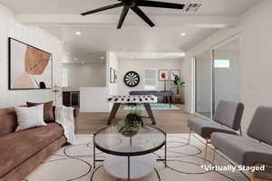 Living area featuring light wood-type flooring, beamed ceiling, and ceiling fan