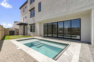Back of property with a patio area, a jacuzzi, stucco siding, a fenced backyard, and a pergola