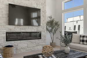Living room featuring wood finished floors, a fireplace, and a high ceiling
