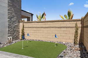 Fenced backyard featuring an area to practice putting