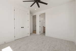 Unfurnished bedroom featuring light colored carpet, ensuite bath, recessed lighting, a ceiling fan, and a closet