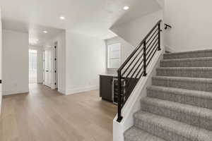 Stairs featuring wood finished floors, recessed lighting, and wine cooler