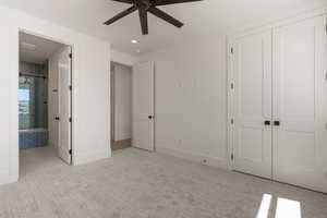 Unfurnished bedroom featuring light colored carpet, a closet, connected bathroom, and a ceiling fan