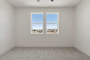 Empty room featuring light carpet and a ceiling fan