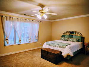 Bedroom with a textured ceiling, carpet flooring, and a ceiling fan