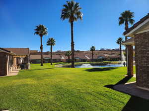 View of green lawn with a patio, a water view, and a residential view