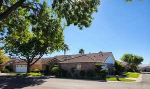 Ranch-style home featuring a tiled roof, brick siding, driveway, and a front yard