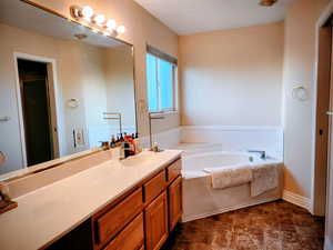 Full bath with a garden tub, vanity, and a stall shower