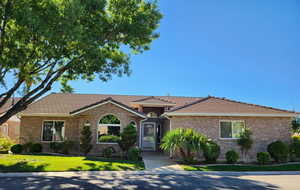 Ranch-style home with a front lawn, a tile roof, and brick siding
