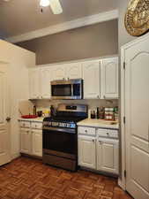 Kitchen featuring white cabinetry, stainless steel appliances, light countertops, and a ceiling fan