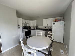 Kitchen with dark countertops, backsplash, and white cabinets
