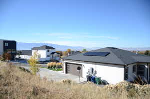 Garage featuring a mountain view, driveway, and roof mounted solar panels