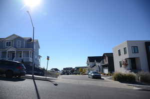 View of asphalt road featuring a residential view, curbs, sidewalks, and street lights