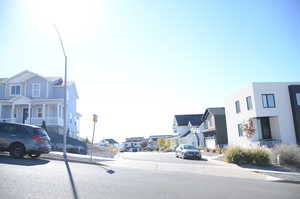View of asphalt road with a residential view, sidewalks, curbs, and street lights