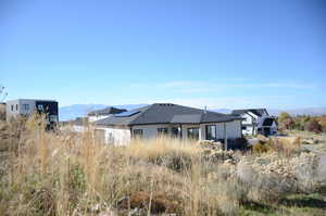 Rear view of house with a mountain view, stucco siding, and solar panels