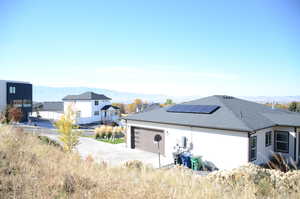 Garage with a mountain view, solar panels, and concrete driveway