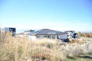 Rear view of house featuring a mountain view, roof mounted solar panels, and stucco siding