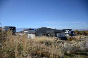View of side of home featuring a mountain view, solar panels, and stucco siding