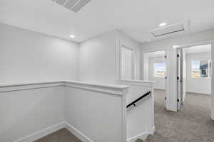 Hallway featuring an upstairs landing, light carpet, and recessed lighting