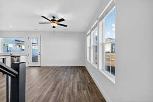 Unfurnished living room with dark wood finished floors, plenty of natural light, and ceiling fan