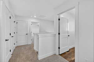 Hall with recessed lighting, an upstairs landing, and carpet