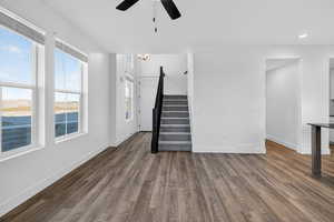 Unfurnished living room featuring stairway, dark wood finished floors, recessed lighting, and ceiling fan