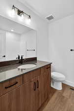 Half bathroom with dark wood-style flooring and vanity