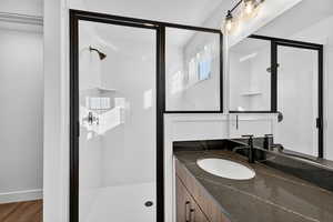 Full bath featuring a shower stall, vanity, and wood finished floors