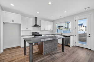 Kitchen with decorative backsplash, a kitchen breakfast bar, wall chimney range hood, white cabinetry, and dark wood finished floors