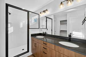 Full bath with a walk in closet, double vanity, and a stall shower