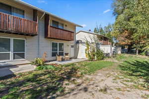Rear view of property featuring a balcony, a patio area, and a lawn
