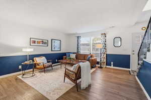 Living room with stairs, a textured ceiling, and wood finished floors