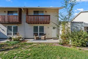 Rear view of property featuring a balcony, a patio, and a yard