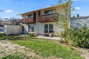Rear view of property featuring a balcony, a patio area, and a storage shed