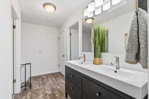Bathroom with double vanity, a textured ceiling, and dark wood finished floors