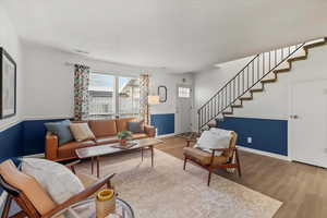 Living area featuring wood finished floors, stairs, and a textured ceiling
