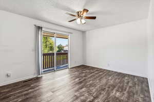 Unfurnished room with dark wood-style flooring, a textured ceiling, and ceiling fan