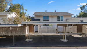 Rear view of house featuring roof with shingles and covered parking
