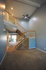 Staircase with high vaulted ceiling, carpet, beam ceiling, and ceiling fan