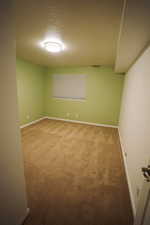 Carpeted empty room featuring a textured ceiling and baseboards