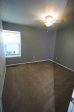 Empty room featuring a textured ceiling and dark colored carpet